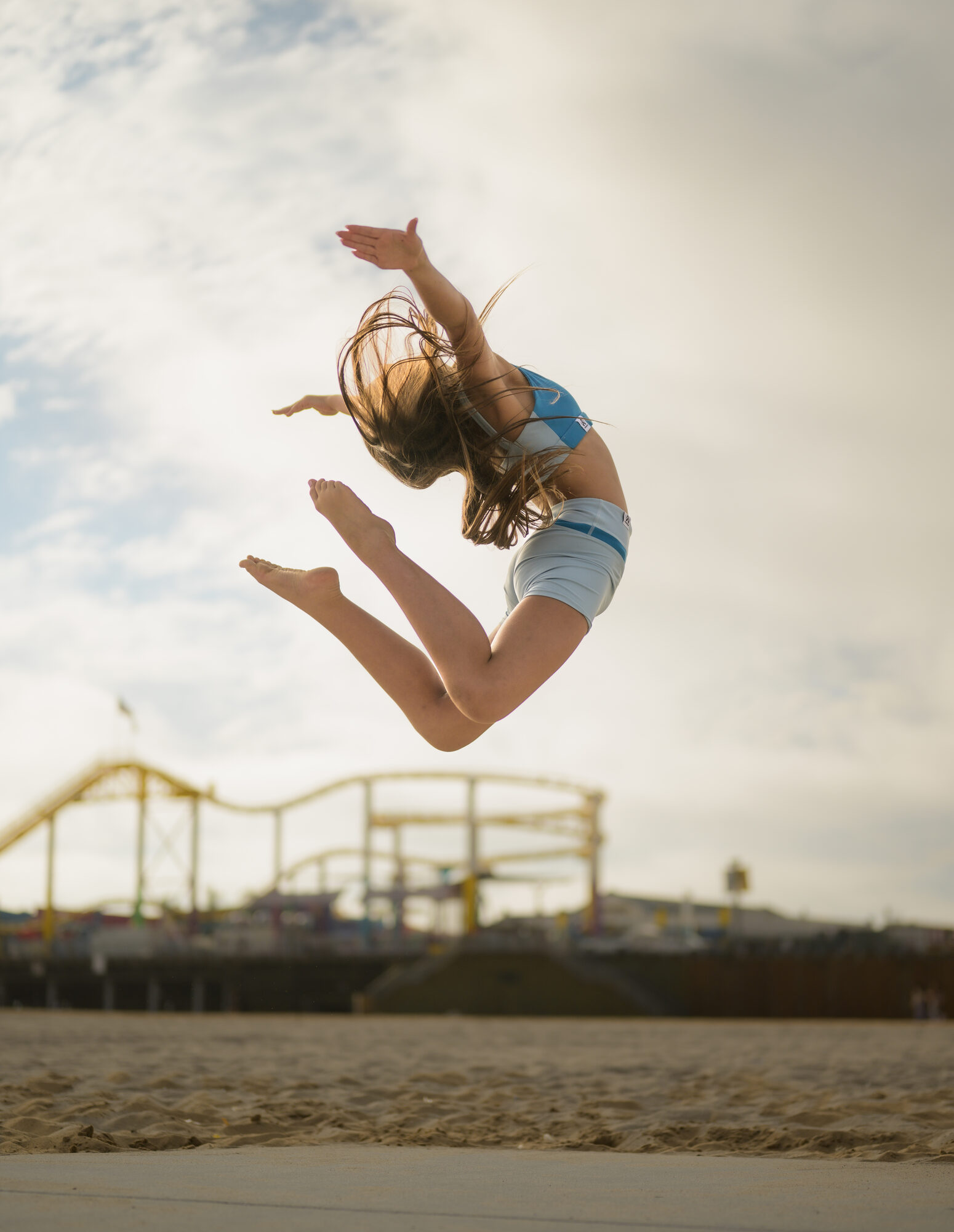 A dancer mid-leap on the beach, arms extended
